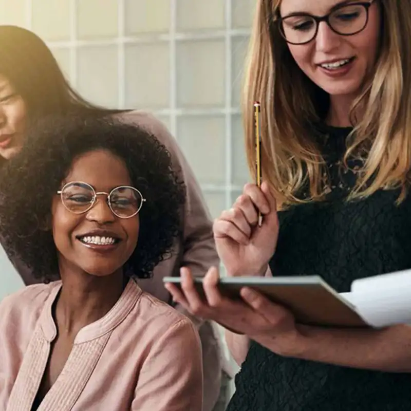 Group of female coworkers looking at paperwork laughing.