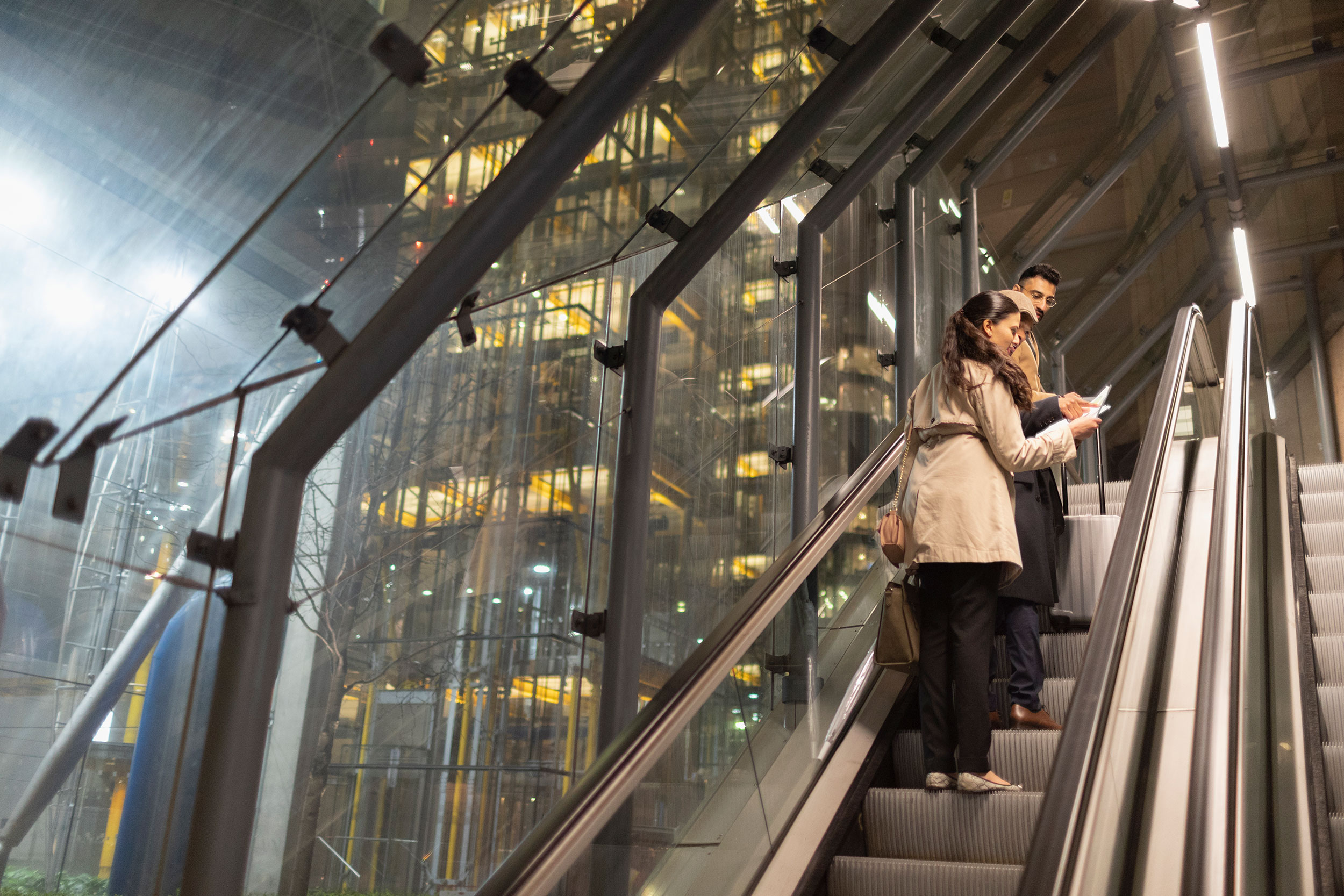 Two people talk while using an escalator