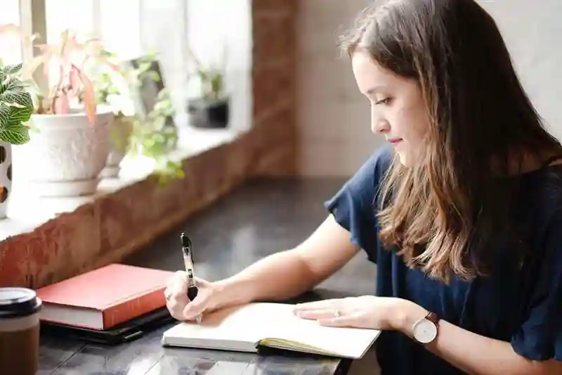 Woman sitting at a desk writing in a journal