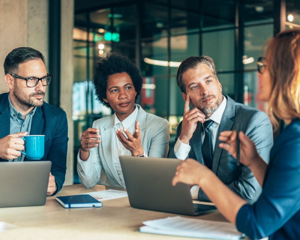Four people with computers and documents having a discussion
