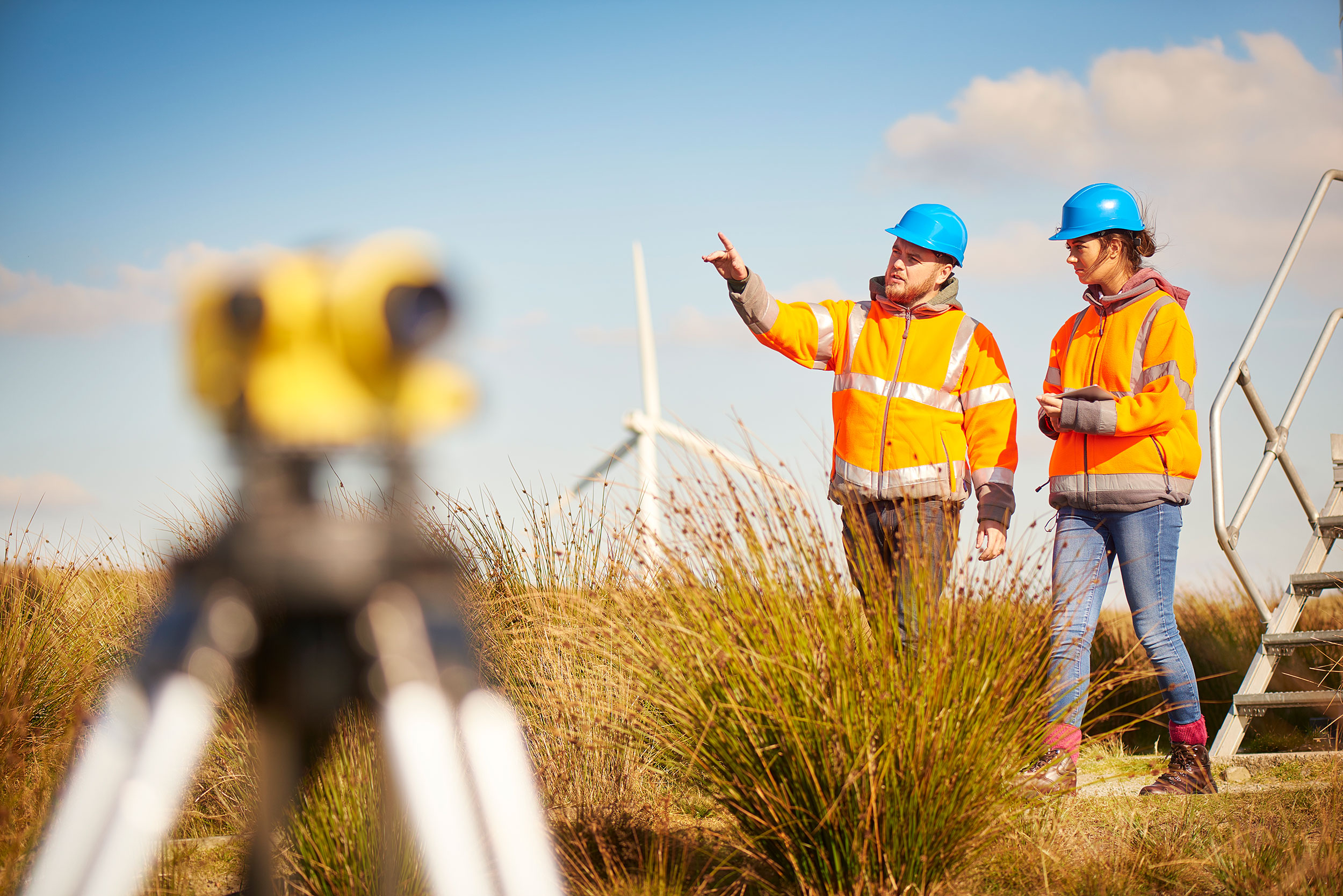 Two surveyors work at a wind farm