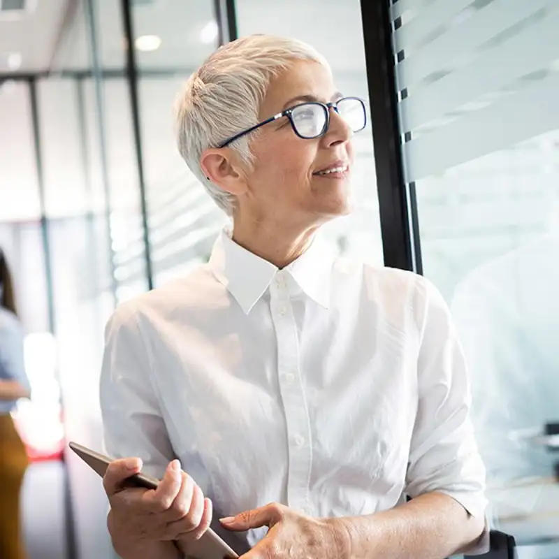 Older woman walking through office with her tablet.
